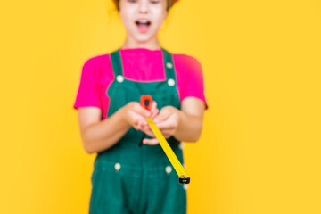 happy kid engineer with tape measure tool in hard hat, measuring, selective focus