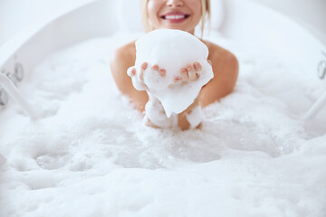 Charming young woman playing with foam in bath