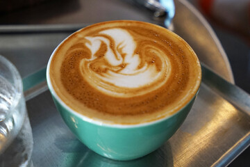 Close up ceramic mug of hot latte art coffee on metal tray