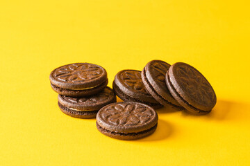 Chocolate sandwich cookies with vanilla cream filling on yellow background.