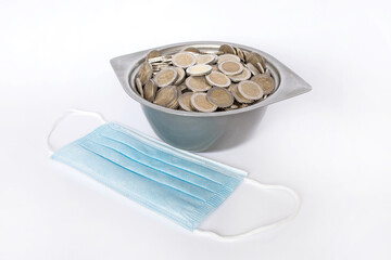 Dirty coins in a metal bowl. White background. Medical mask. Lithuanian money