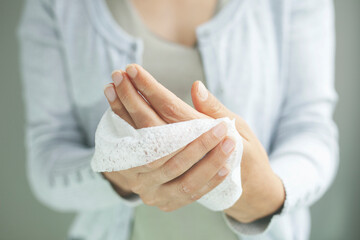 Woman cleaning her hands by using white tissue paper. isolated on a gray background.