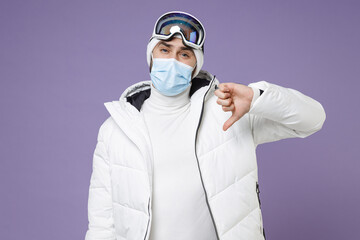 Upset skier man in warm white windbreaker jacket ski goggles face mask safe from coronavirus virus...