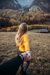 Naklejka na ściany i meble Young woman holding man hand. focused on hand, nature and adventure travel concept
