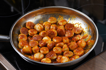 German currywurst. Fried sausages with sauce in the pan.