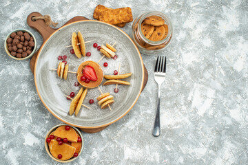 Yummy pancakes with fruits on cutting board chocolate cookies biscuits on blue backgound