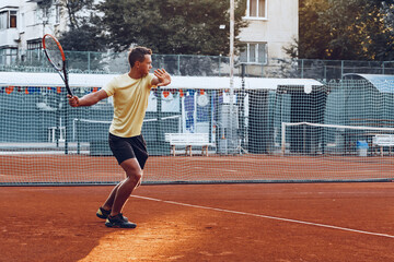 Obraz premium Young handsome man playing tennis on the tennis court