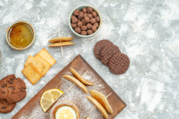 Above view of simple pancakes with lemons on cutting board and cookies honey on blue background