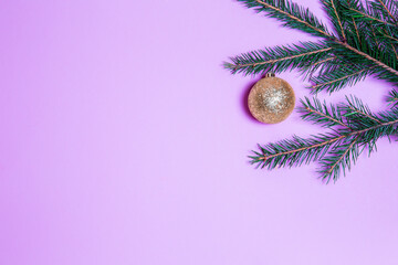 Christmas Christmas-tree toys of gold color on a pink background among the fir branches covered with snow. View from above. space for text layout