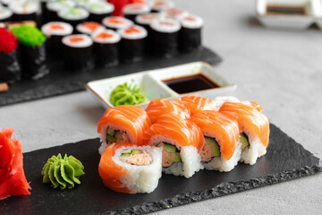 Sushi roll covered with fresh salmon served on plate