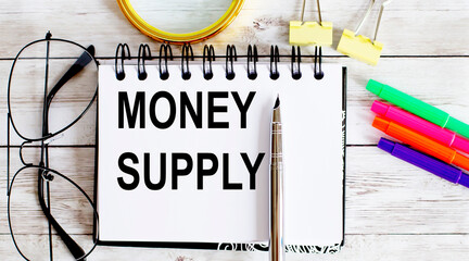 Blank sheet, pen and glasses on the grey table. MONEY SUPPLY