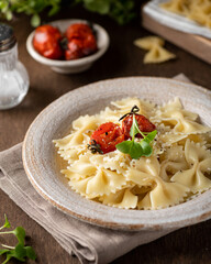 Farfalle pasta in a ceramic plate on a wooden background, selective focus