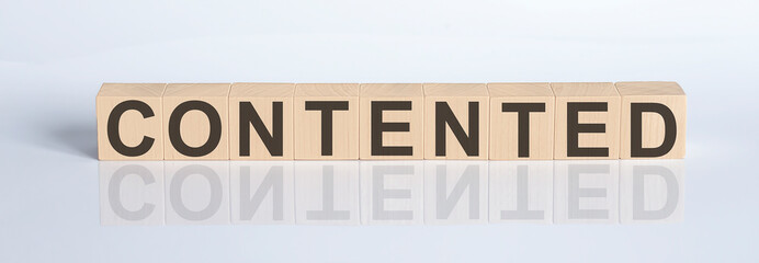 CONTENTED word from wooden blocks on the white desk