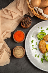 Half shot of homemade cutlet meal along with potatoes with spices and towel on dark table