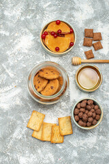 Obraz na płótnie Canvas Vertical view of homemade cakes and chocolate biscuits in a glass jar on blue background