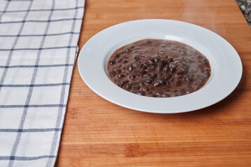 White plate with black beans on a wooden board