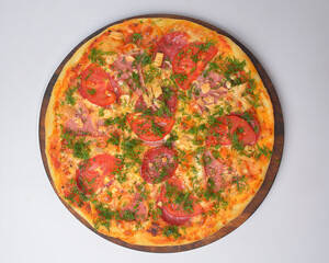 Pizza pollo with chicken meat, tomatoes and ham served on a round wooden board over white background.