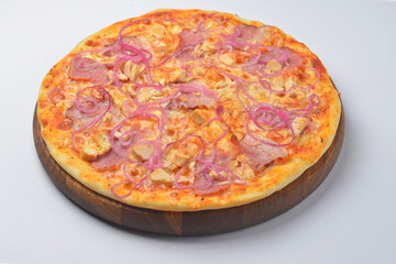 Pizza with meat and caramelized onions served on a round wooden board over white background.