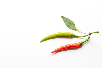 close up of chillies pepper in green, orange, and red colors with green leaves isolated on white background with copy space for texting.