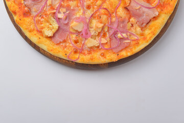 Pizza with meat and caramelized onions served on a round wooden board over white background.