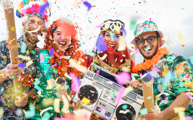 Young people wearing colorful costumes celebrating carnival party event throwing confetti outdoor