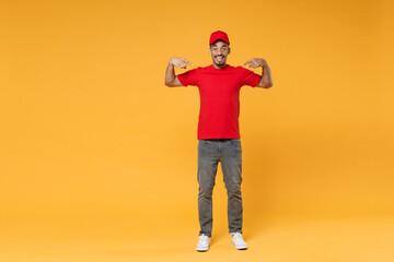 Full length delivery employee african man 20s in red cap blank print t-shirt uniform workwear work courier dealer service during quarantine covid-19 virus concept isolated on yellow background studio.
