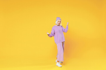 Fototapeta na wymiar Full length of young blonde caucasian woman 20s bob haircut in casual basic purple suit beanie hat doing winner gesture clenching fists saying yes isolated on yellow background studio portrait.