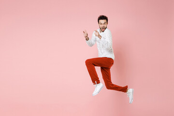 Fototapeta na wymiar Full length side view of shocked young bearded man 20s wearing basic casual white shirt jumping keeping mouth open pointing index fingers aside isolated on pastel pink wall background studio portrait.
