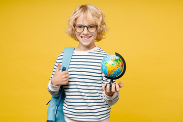Smiling male kid teen boy 10s years old in striped sweatshirt eyeglasses backpack hold world Earth globe showing thumb up isolated on yellow color background, child studio portrait. Education concept.