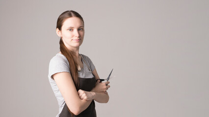 Naklejka premium Hairdresser holding scissors at gray studio background