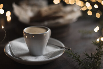 Espresso surrounded by New Year's lights and pine branches. Food dark background. Christmas lunch in a cafe