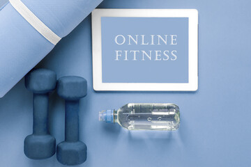 flatlay blue: tablet with the inscription online fitness, sports mat, dumbbells and a bottle of water 