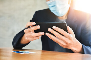 Businessman in face mask using mobile smartphone to working online focus on hand
