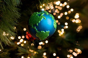 Close-up of Christmas bauble decoration ornament globe planet earth  on the background of the Christmas tree. Merry christmas and new year concept. Selective focus