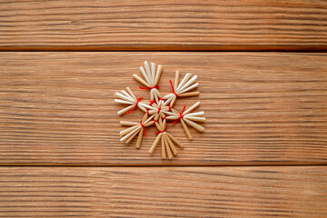 Straw snowflake in the center. Top view, wooden background