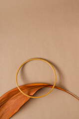 Vertical image of dry brown leaf, wooden ring on the light brown surface.Empty space