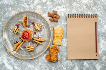 Buttermilk pancakes with fruits and cookies biscuits next to notebook on blue background