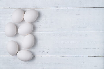 White raw chicken eggs on white wooden boards background with copy space.
