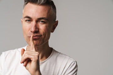 Serious man with finger on lips keeping a secret