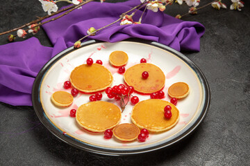 front view yummy little pancakes with red berries on a dark background sweet milk dessert