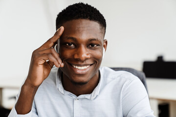 Afro american joyful man in earphones smiling at camera