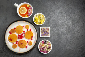 top view yummy pancakes with cup of tea on a dark background sweet pie dessert cake