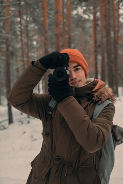 young man taking pictures of beautiful winter forest