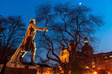 Mannheim, Germany. April 19th, 2010. Evening shot of the statue dedicated to Friedrich Schiller at the Schillerplatz in Mannheim. In the background beyond the trees, the Jesuit Church.