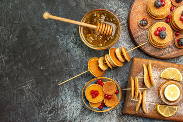 Above view of stuffy pancakes on cutting board and honey on the left side of the gray table