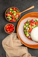 Vertical view of vegan dinner with rice and different types of vegetables on dark background