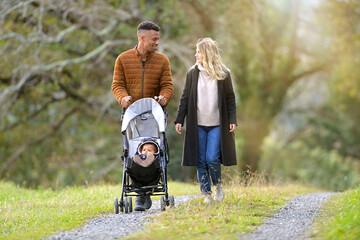 Couple with baby in stroller, walking outside in countryside
