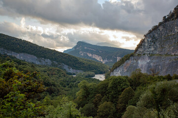 Mountain gorge with river below against cloudy cloudy sky
