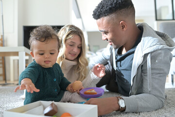 Young parents playing with baby girl at home