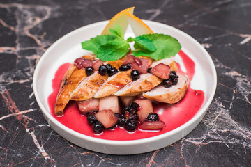 Delicious and juicy chicken with melon and berries on a white plate